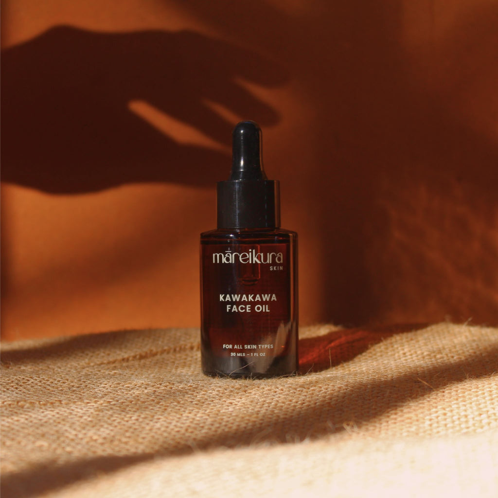 Kawakawa face oil bottle on a textured surface with a warm brown background