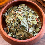 Dried relax tea leaves, displayed in a round wooden bowl on a wooden table.