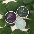 Three tins of House of Rehua balms on kawakawa leaves
