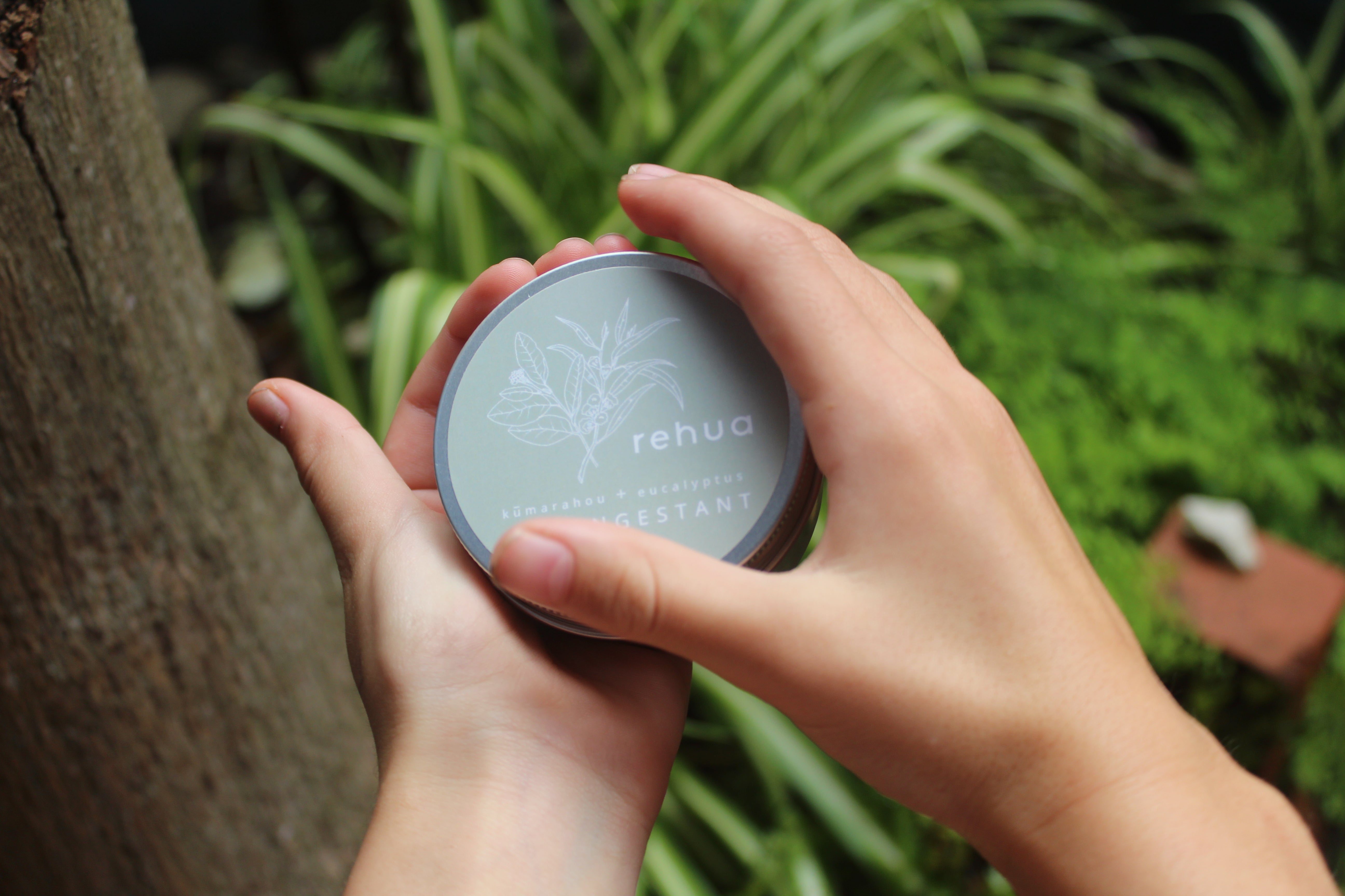Person holding 'rehua' decongestant rub against a natural background