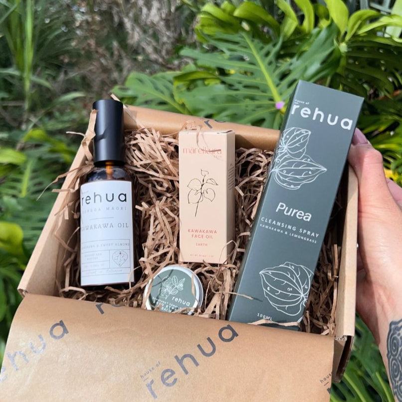 Box of Rehua products with a hand holding a gift box, against a green leafy background.