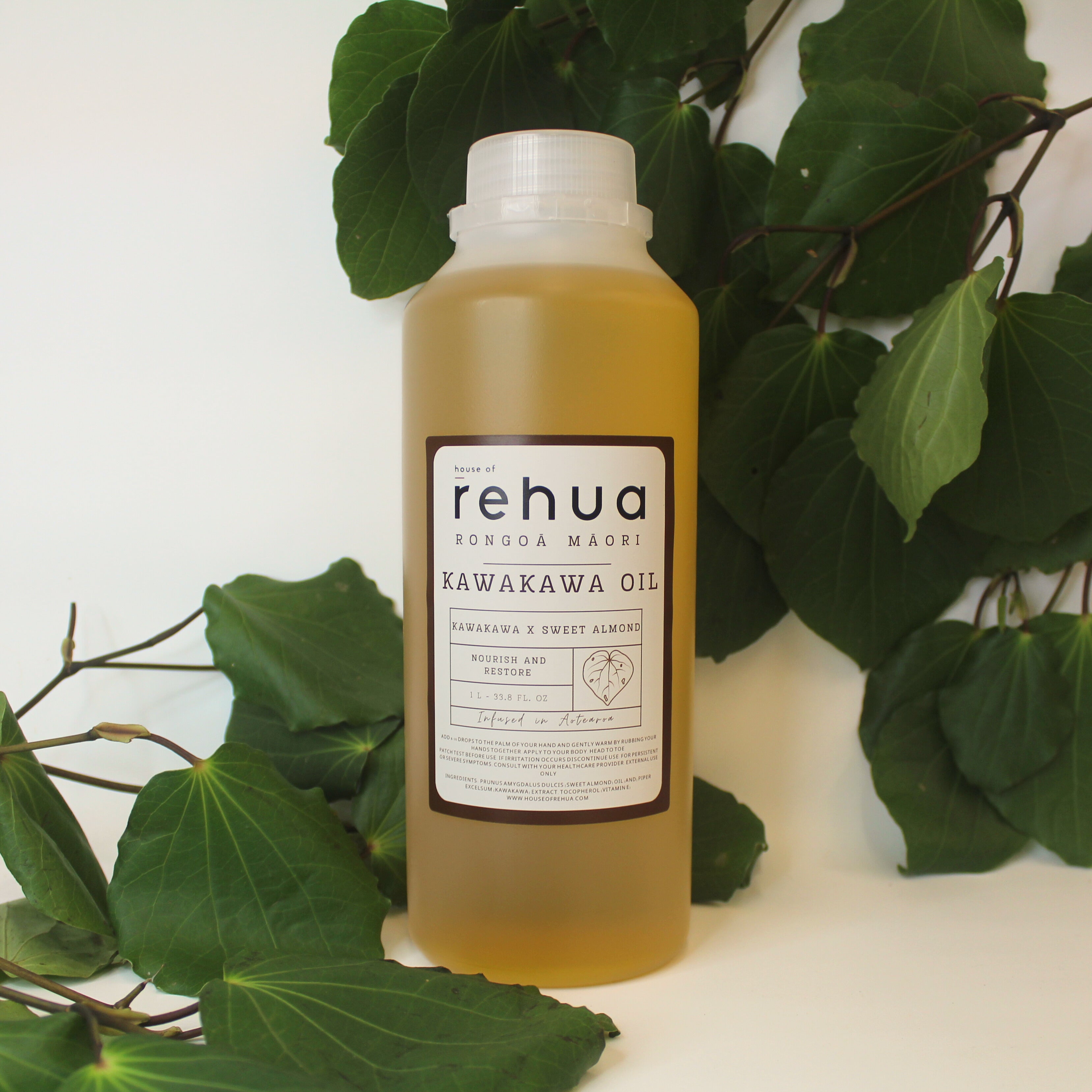 House of Rehua one litre bottle of kawakawa oil with kawakawa leaves in the background