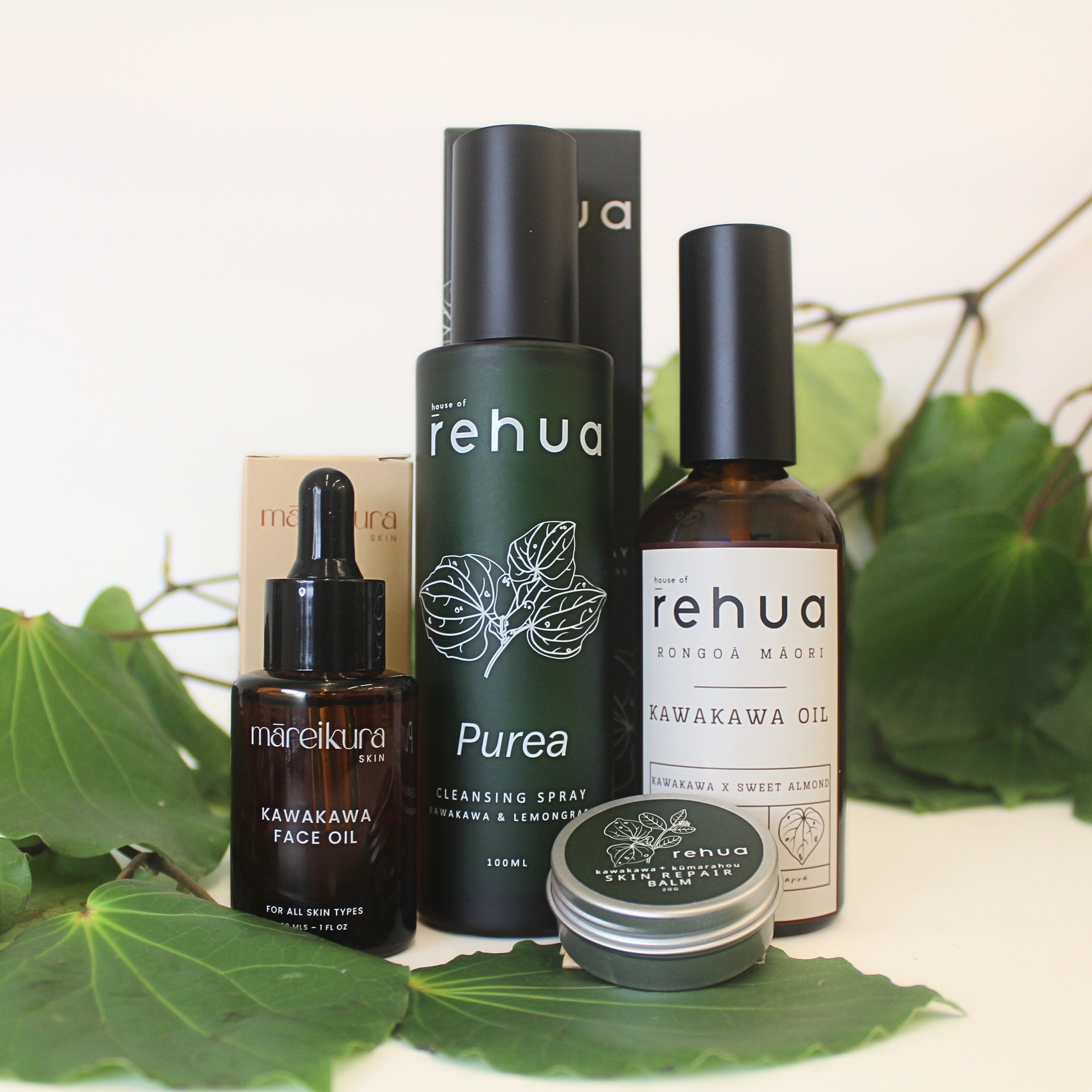 Collection of House of Rehua and Māreikura Skin kawakawa products on a white background with kawakawa leaves.
