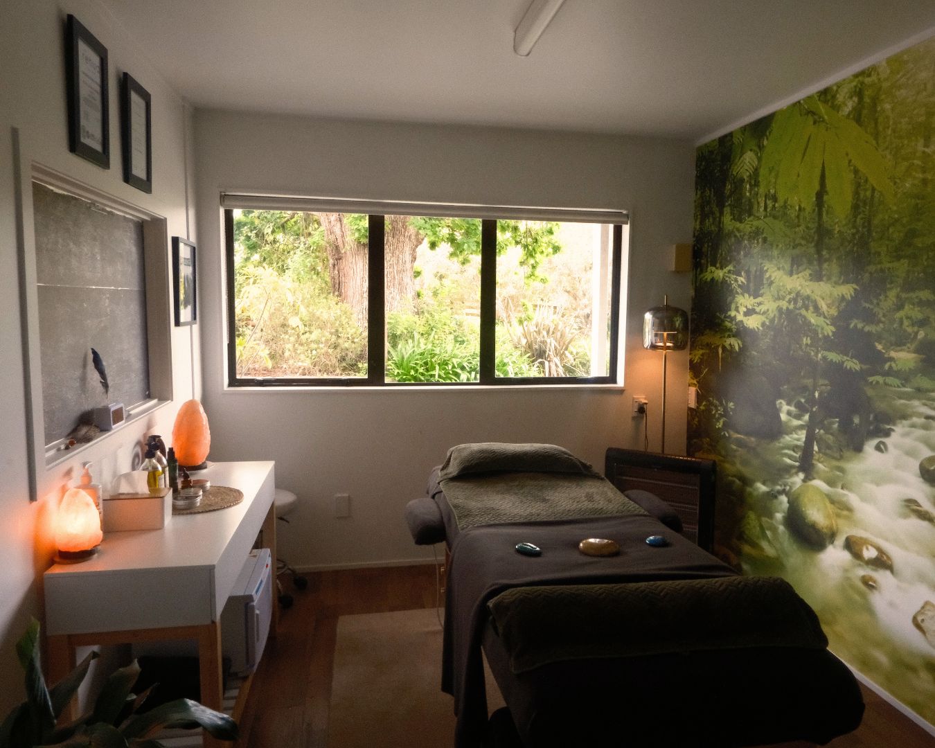 Meditation or therapy room with a large window, massage table, and wall art.