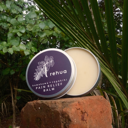 Rehua pain relief balm container with purple lid and beige body on a natural background