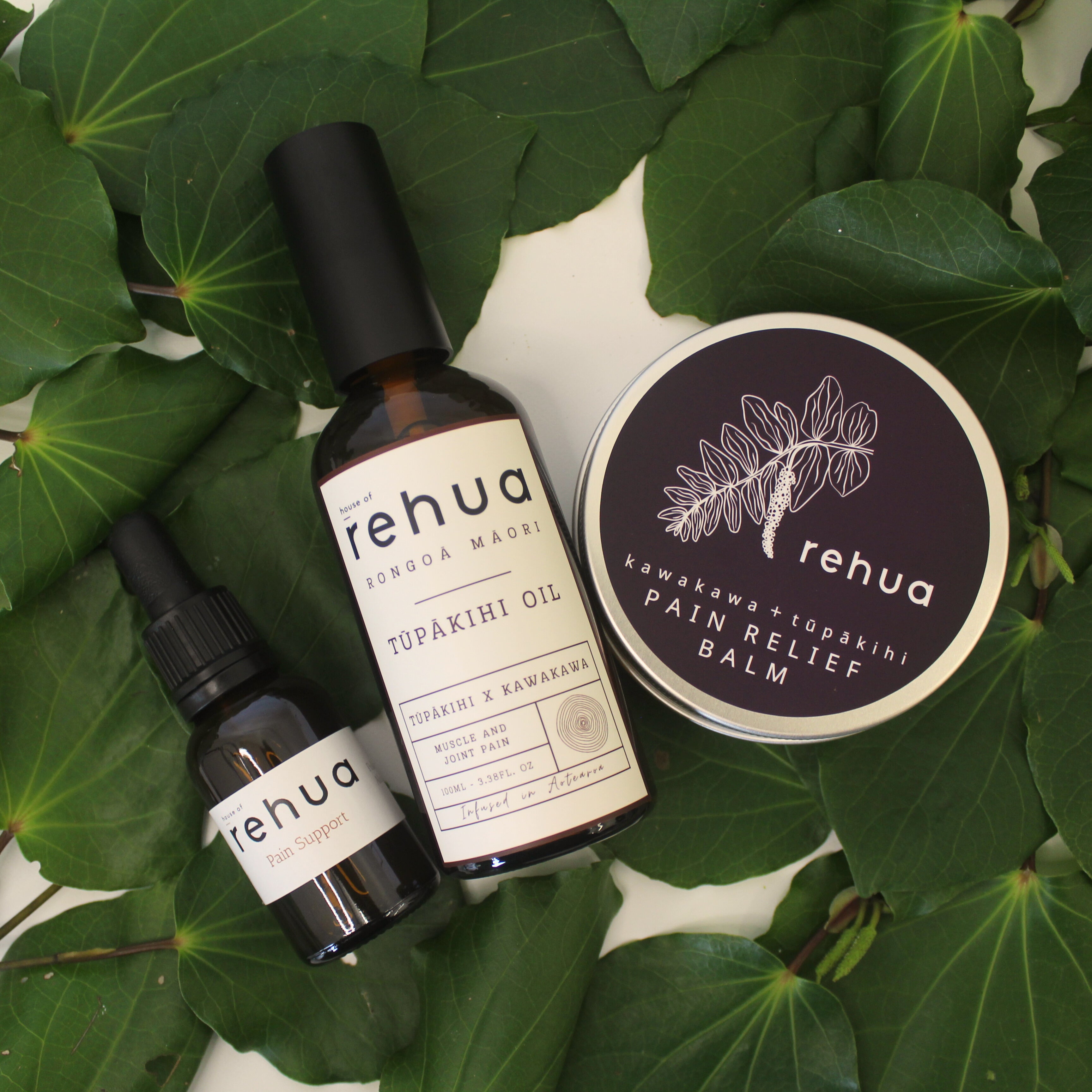 House of Rehua products including oil, balm, and tincture on kawakawa leaves