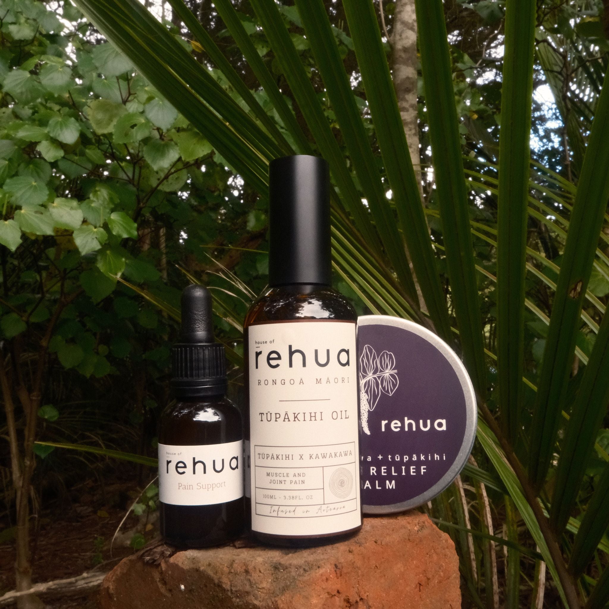 Three Rehua products on a stone surface with green foliage in the background