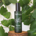 House of Rehua Purea cleansing spray bottle on a wooden stump with kawakawa leaves in the background