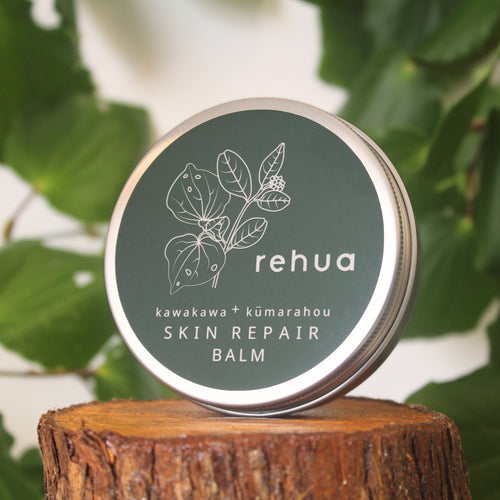 House of Rehua Skin Repair Balm container on a wooden stump with kawakawa leaves in the background