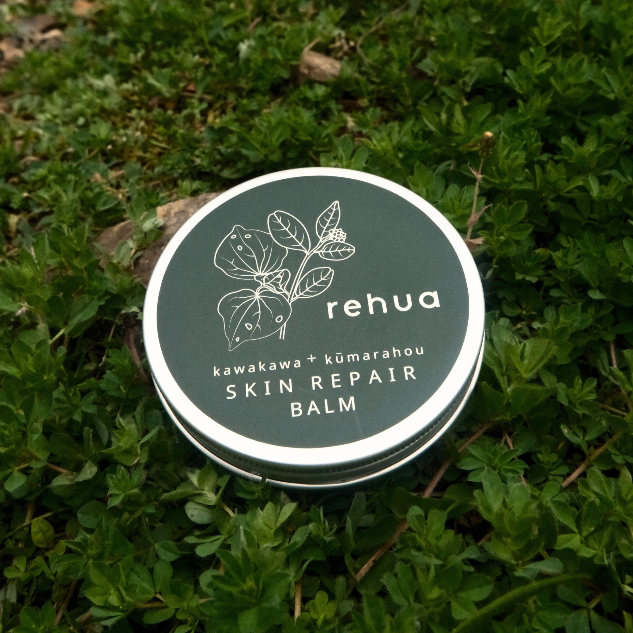 Rehua skin repair balm container on a grass background