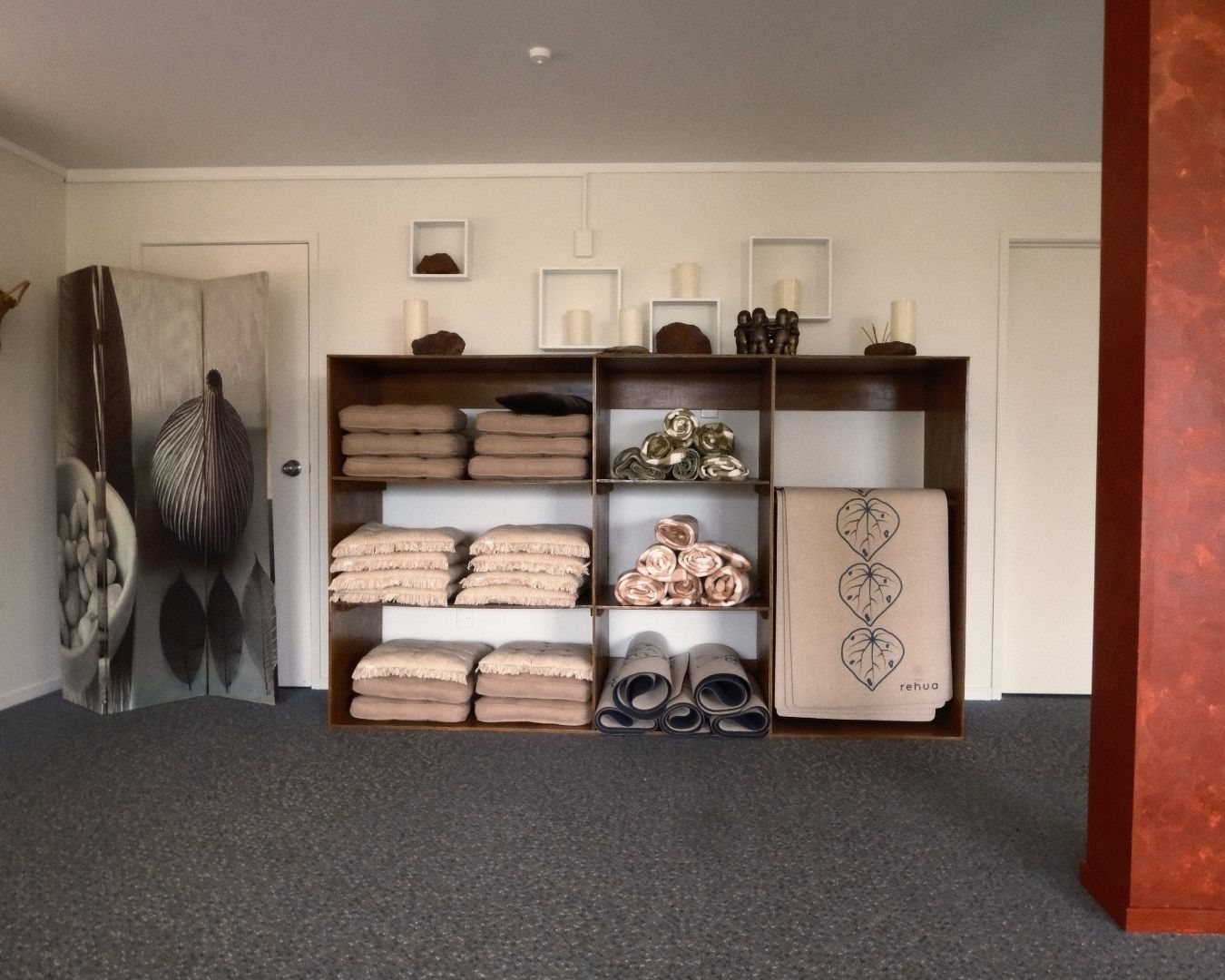 Room with a wooden shelf displaying folded towels and decorative items.