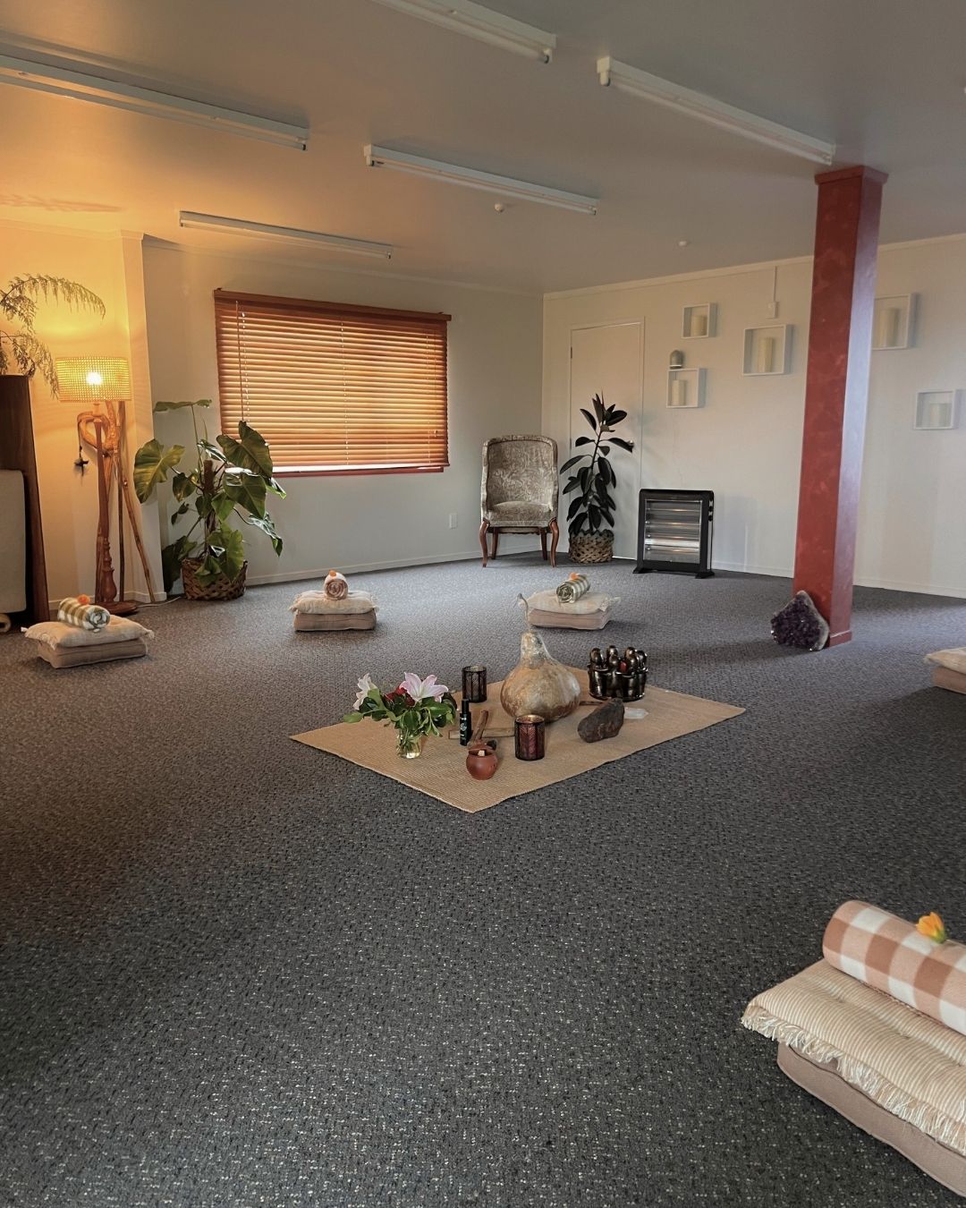 Spacious room with yoga mats, candles, and decorative items on the floor.
