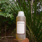 Bottle of rehua Tupakihi oil on a rock with green foliage in the background