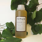 House of Rehua one litre bottle of tupakihi and kawakawa oil with kawakawa leaves in the background