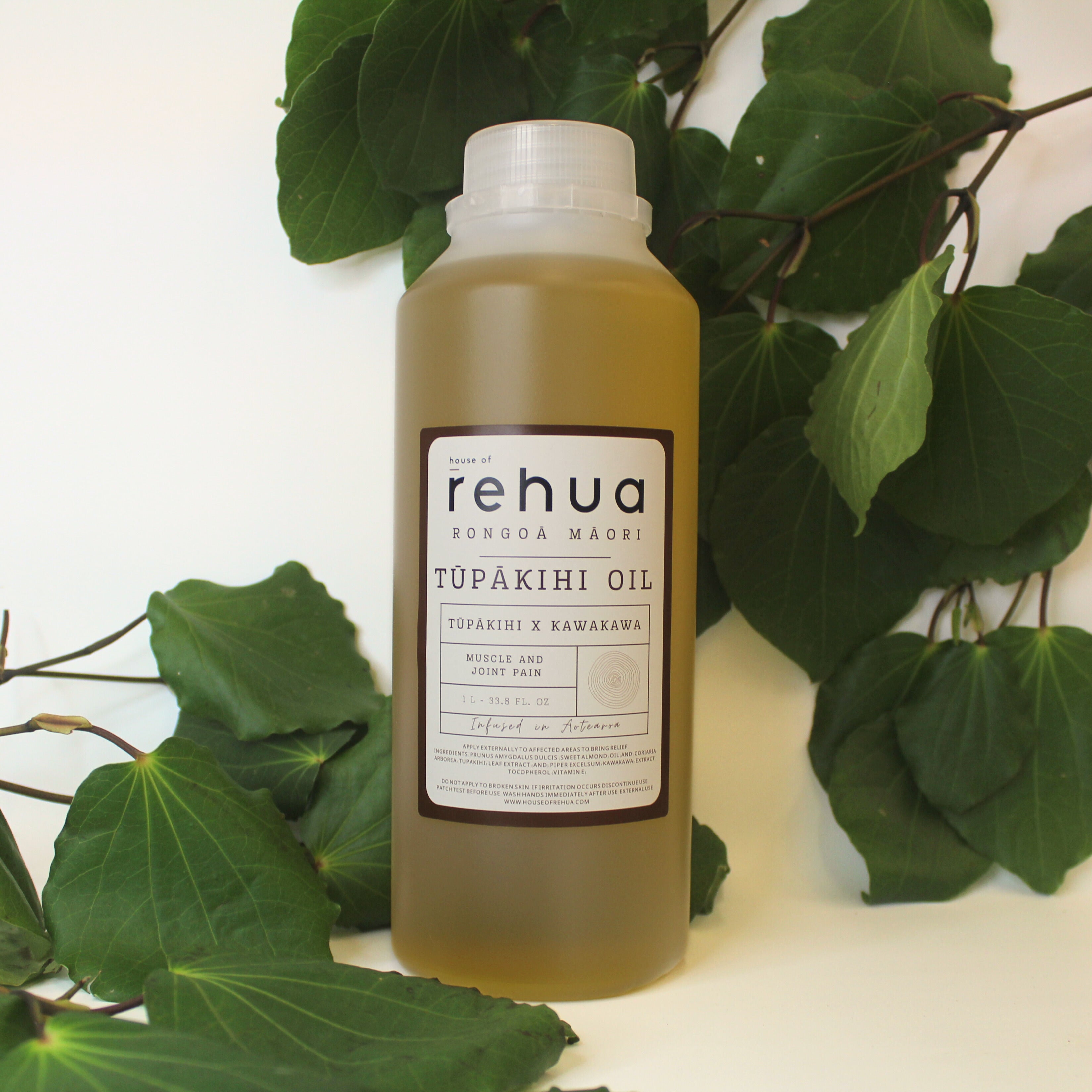 House of Rehua one litre bottle of tupakihi and kawakawa oil with kawakawa leaves in the background