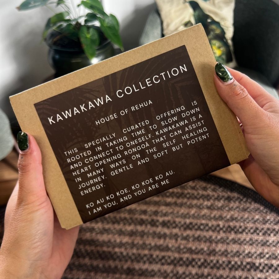 Person holding a box with 'Kawakawa Collection' text against a blurred indoor background