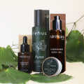 A skincare set from the brands rehua and mareikura skin, including face oil, cleansing serum, body oil, and skin repair balm, styled with green leaves on a light background.