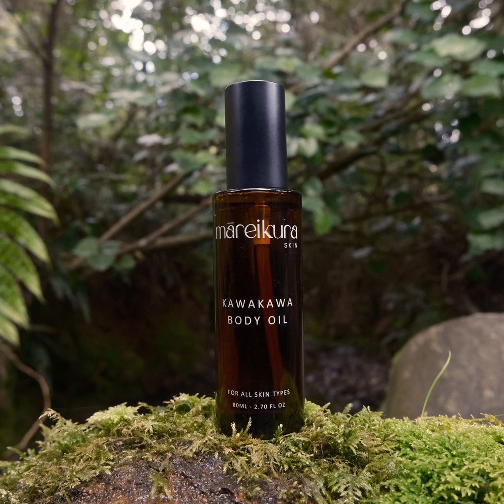Bottle of mareikura Kawakawa Body Oil on a mossy rock with a forest background