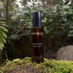 Bottle of mareikura Kawakawa Body Oil on a mossy rock with a forest background