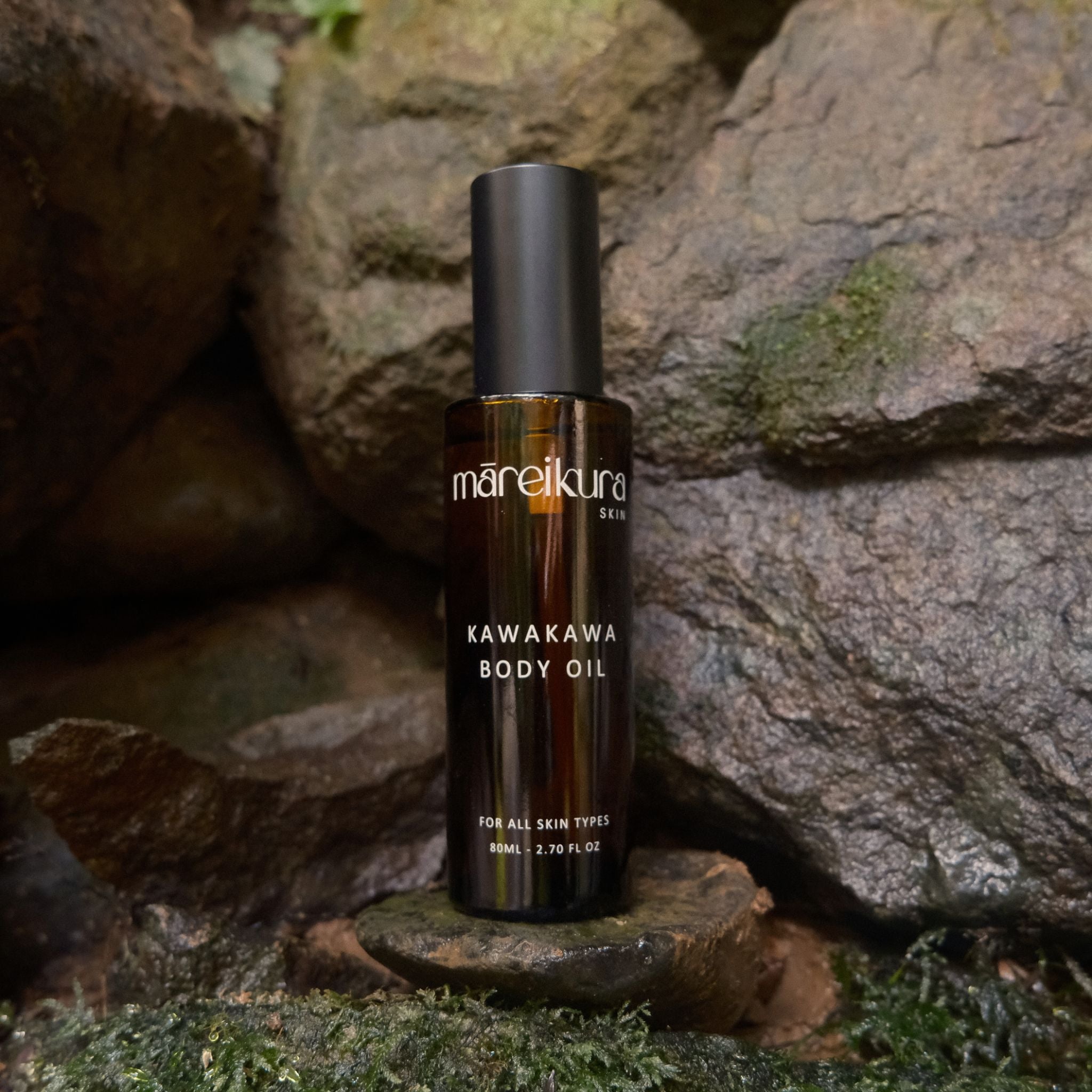 Bottle of Mareikura Kawakawa Body Oil on a stone surface with a natural rock background