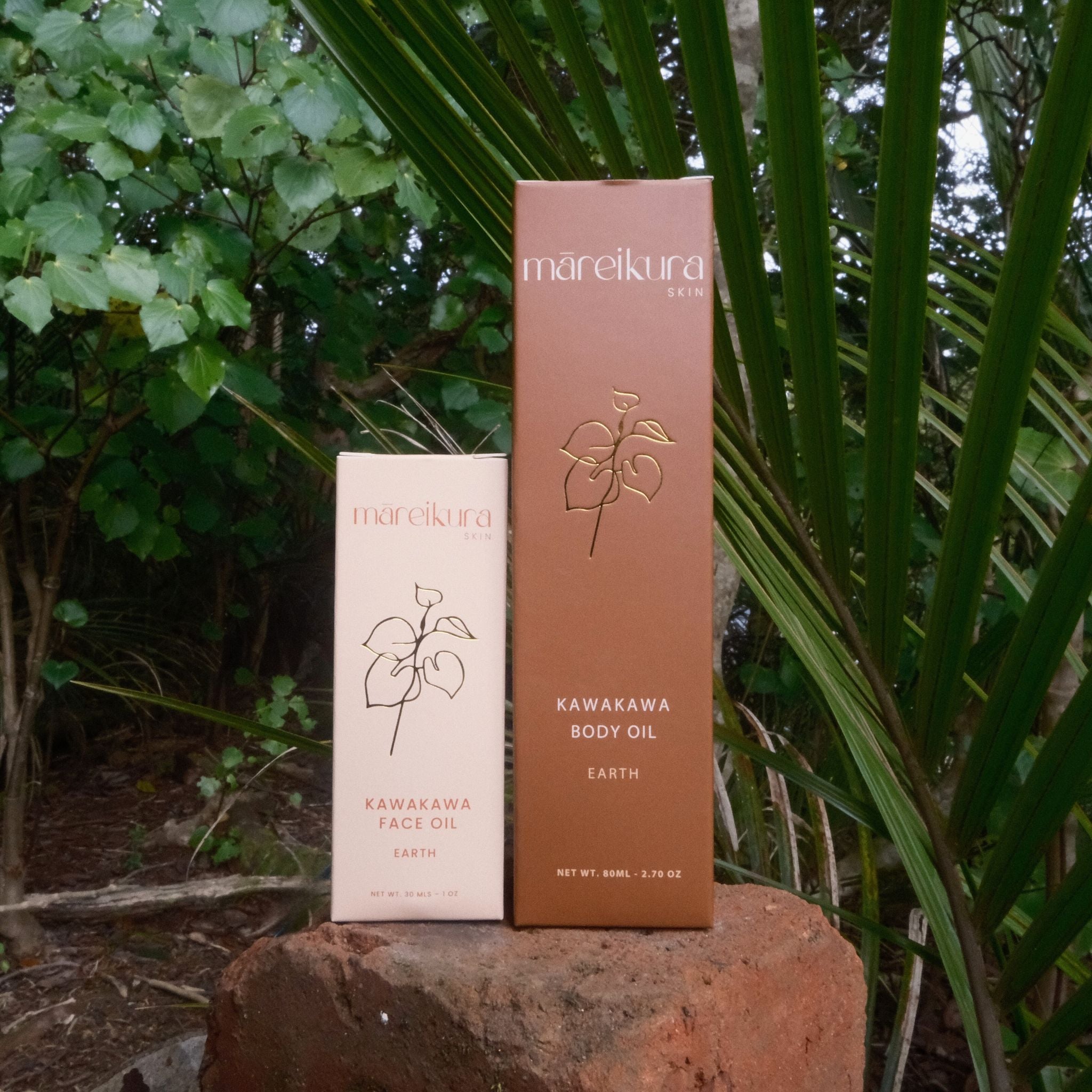 Two boxes of mareikura skincare products on a rock with greenery in the background
