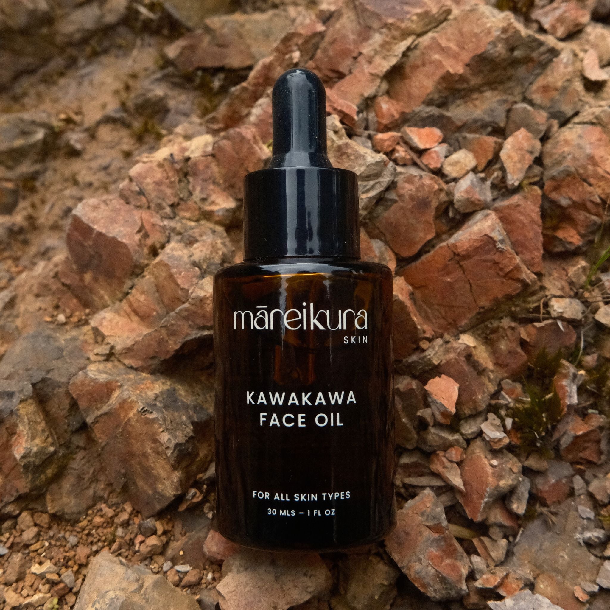 Maneikura Kawakawa Face Oil bottle on a stone background
