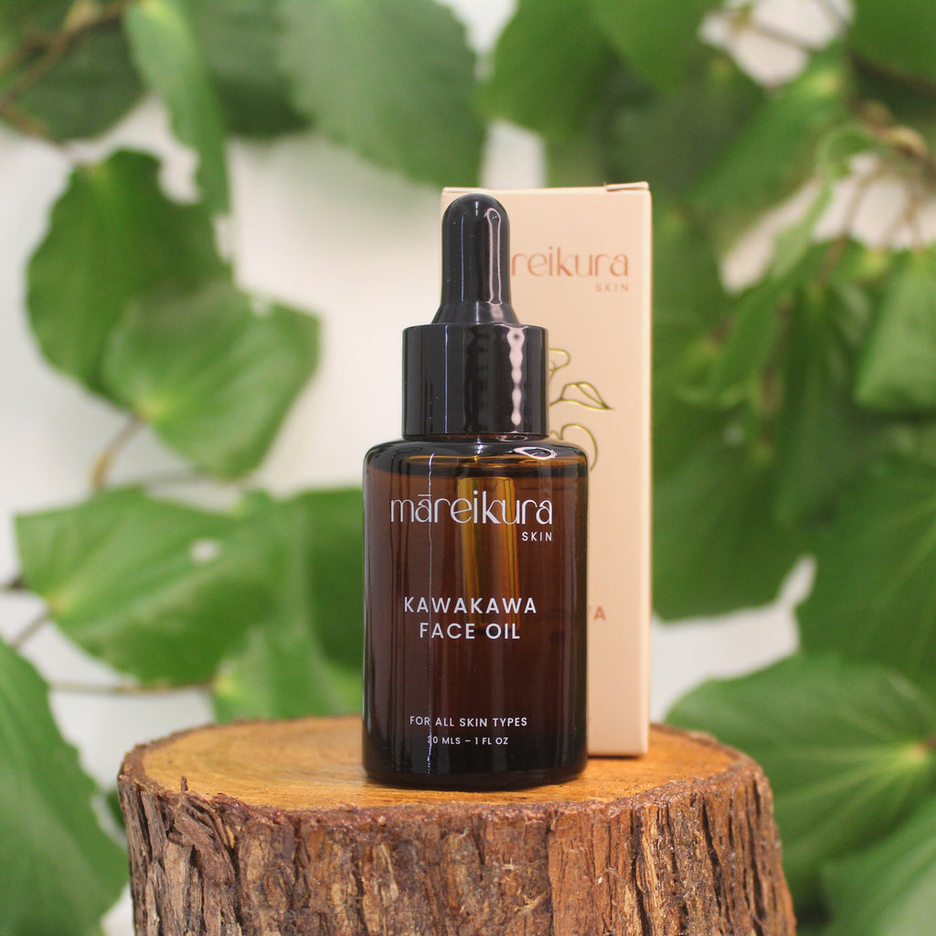 Mareikura Skin Kawakawa Face Oil bottle and box on a wooden stump with kawakawa leaves in the background