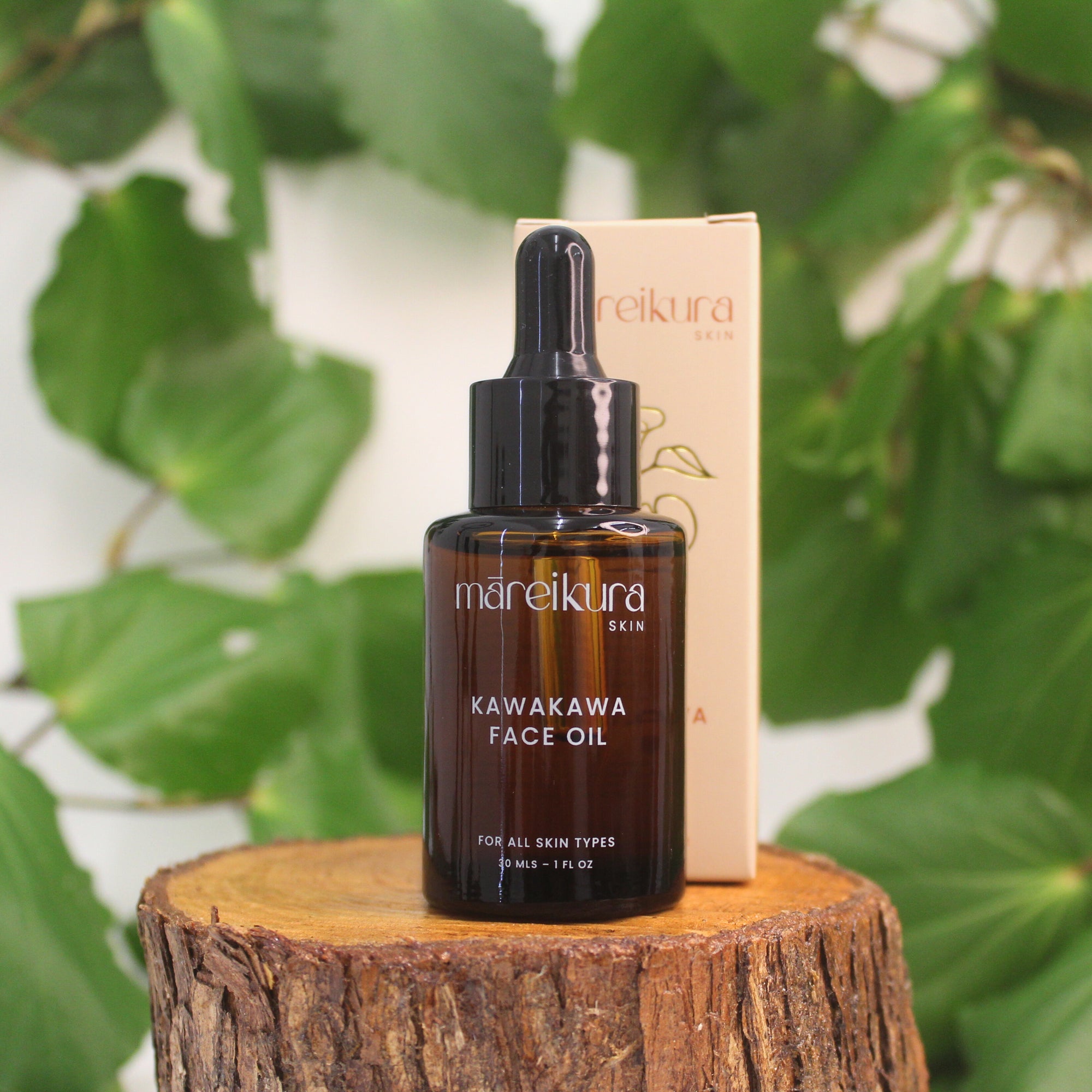 Mareikura Skin Kawakawa Face Oil bottle and box on a wooden stump with kawakawa leaves in the background