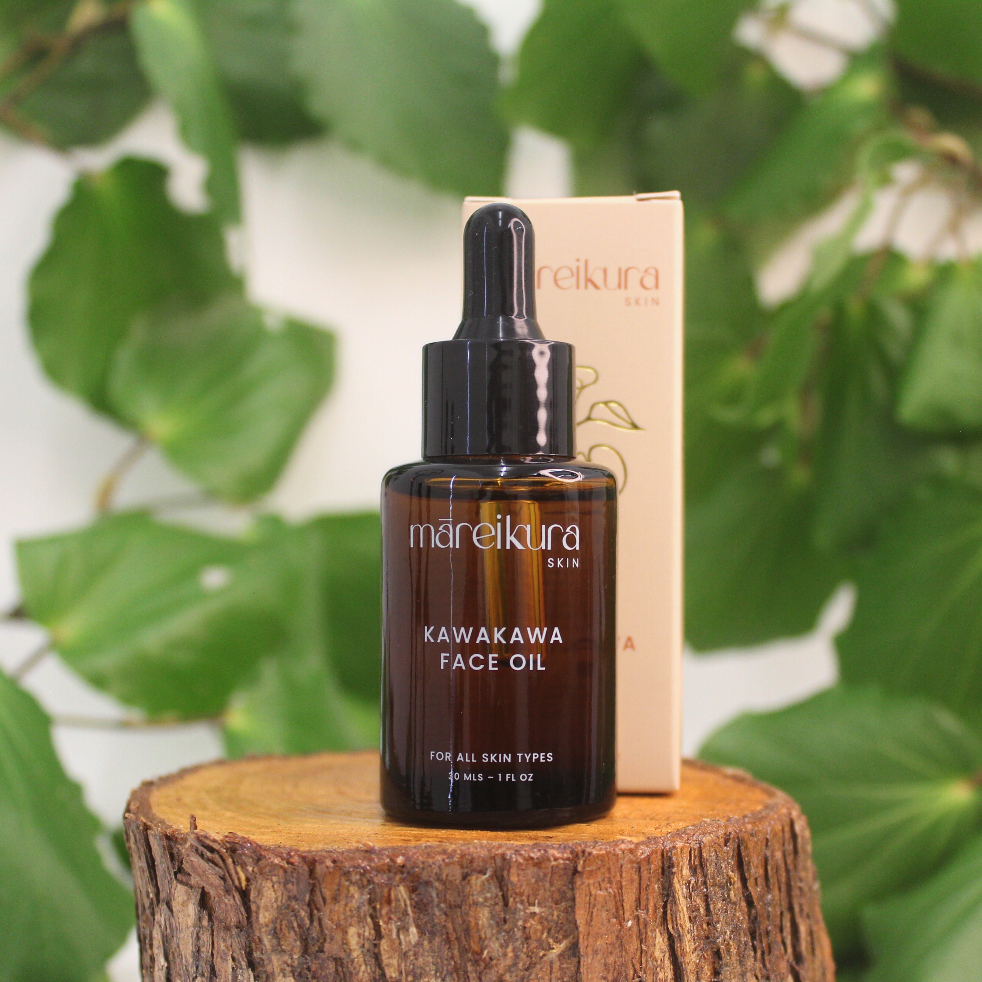 Mareikura Skin Kawakawa Face Oil bottle and box on a wooden stump with kawakawa leaves in the background