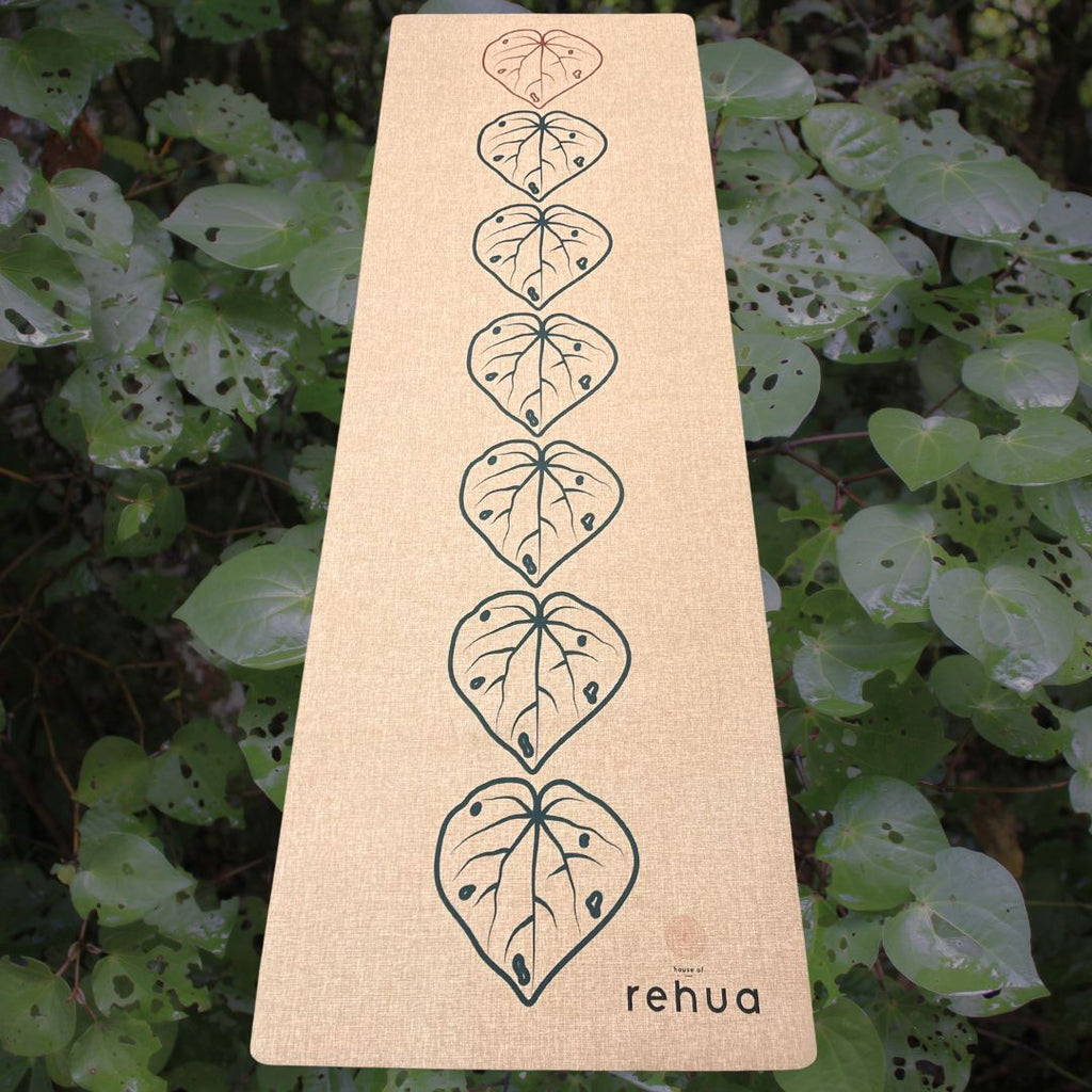 Beige mat with leaf patterns and 'rehua' branding on a green leafy background