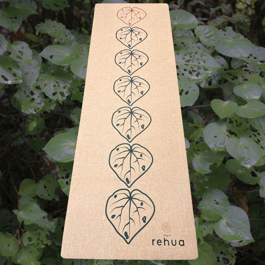 Beige mat with leaf patterns and 'rehua' branding on a green leafy background