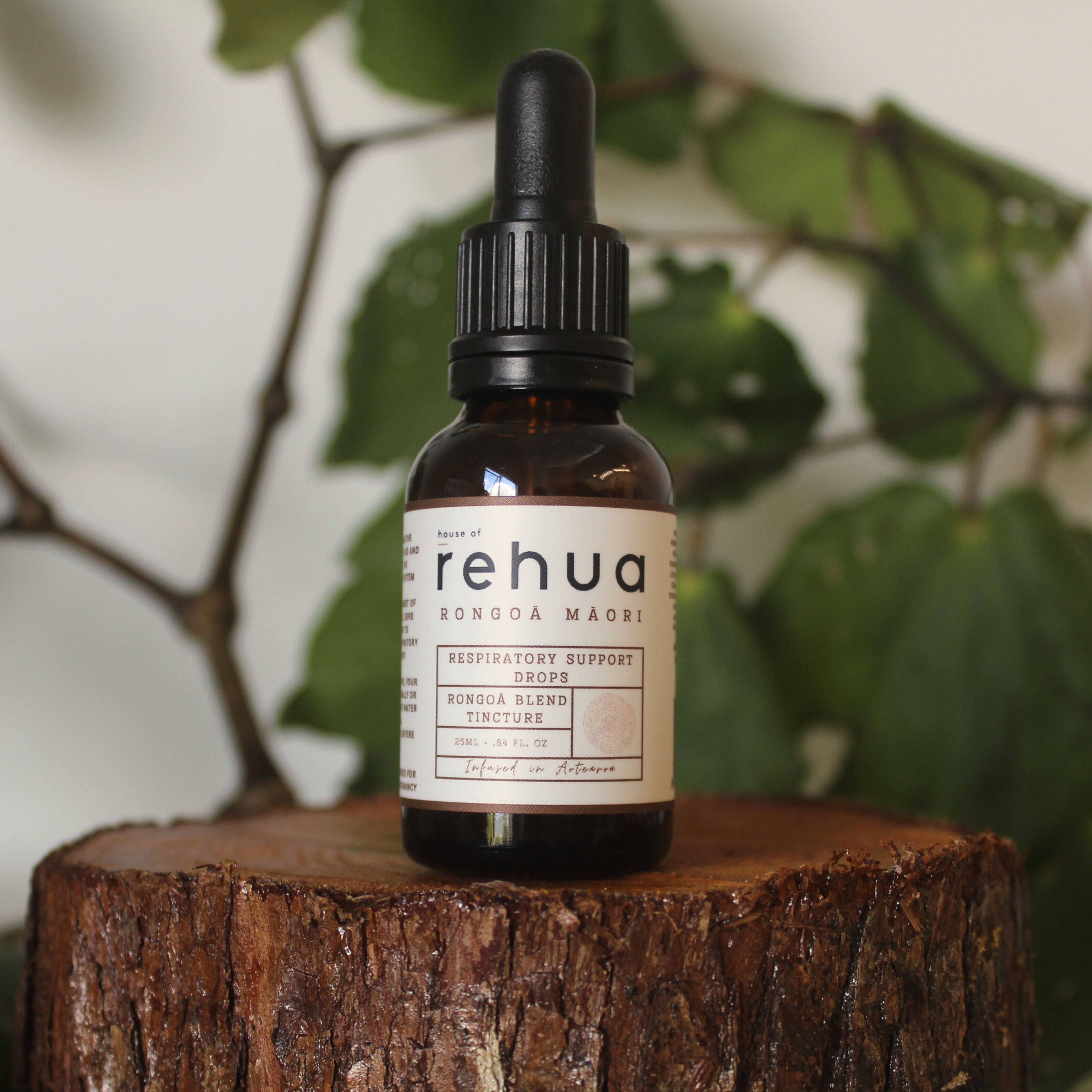 Bottle of Rehua respiratory support drops on a wooden stump with green leaves in the background