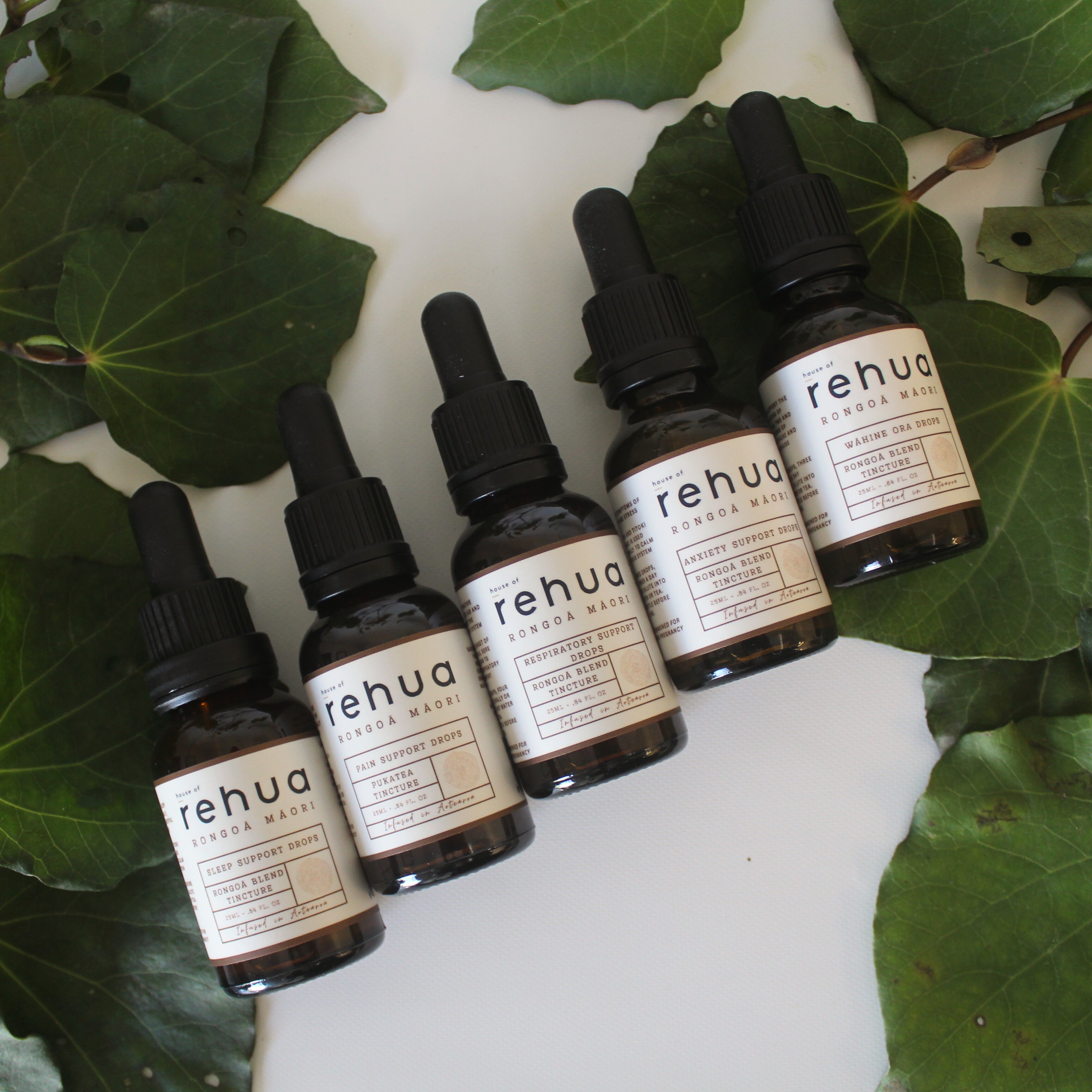 Set of Rehua skincare products on a white surface with green leaves.