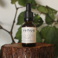 Bottle of Rehua on a wooden stump with green leaves in the background