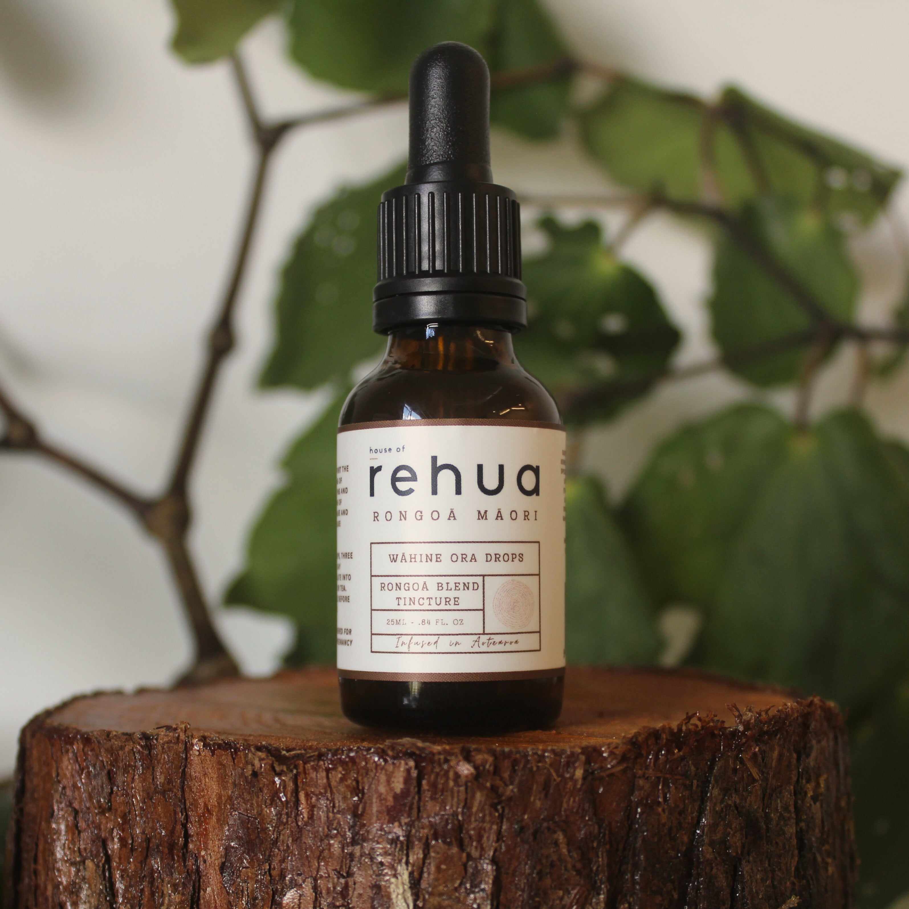 Bottle of Rehua on a wooden stump with green leaves in the background