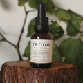 Bottle of Rehua drops on a wooden stump with green leaves in the background